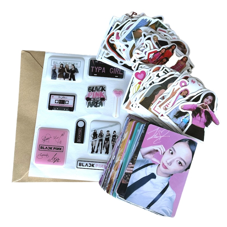 May include: A collection of stickers and photo cards featuring the K-pop group Blackpink. The stickers include images of the group members, logos, and phrases. The photo cards showcase individual members. The items are arranged on a white surface.
