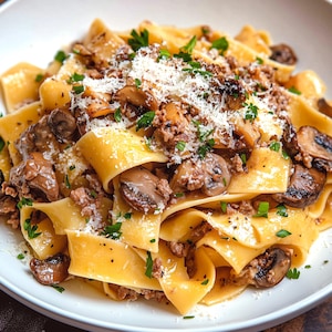 May include: A plate of pasta with a creamy sauce, mushrooms, and minced meat. The pasta is topped with grated cheese.