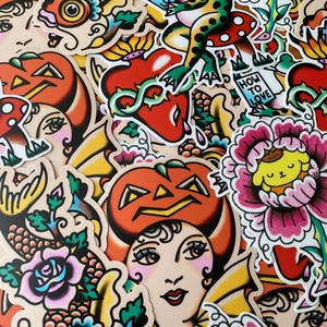 May include: A collection of colorful stickers with a vintage tattoo art style. Designs include a frog on a mushroom, a heart with vines, a pumpkin-headed woman, and various flowers. Some stickers have the text "HOW TO LOVE".