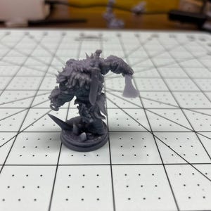 May include: A gray 3D printed miniature of a furry, humanoid creature holding an axe. The miniature is standing on a round base.