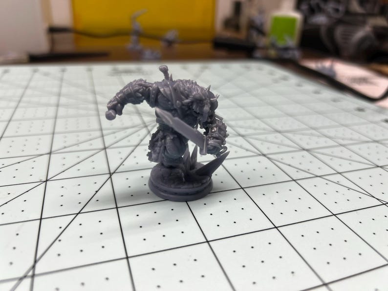 May include: A gray plastic miniature figurine of a fantasy creature holding a sword. The figurine is standing on a round base.
