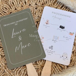 Peut inclure: Deux éventails de mariage avec des manches en bois. L'un est vert olive avec les noms "Laura & Marc" et le texte "Bienvenue au mariage de". L'autre est blanc avec un programme de mariage et des illustrations.