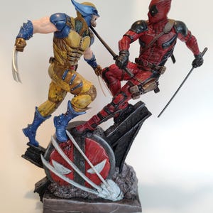 Peut inclure: Un ensemble de figurines d'action détaillées représentant Wolverine et Deadpool dans une pose dynamique. Wolverine est vêtu d'un costume jaune et bleu avec ses griffes déployées, tandis que Deadpool est vêtu d'un costume rouge et noir avec des épées dégainées. Les figurines sont posées sur un socle avec un logo Deadpool rouge et blanc.