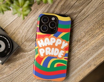 May include: A colorful phone case with the words "HAPPY PRIDE" in white, set against a vibrant rainbow swirl design. The case is on a wooden surface, with a camera and plant in the background.