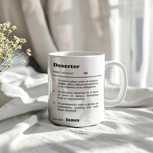 May include: White ceramic mug with a black definition of the word "Deserter" and the name "James" at the bottom. The mug has a black handle.