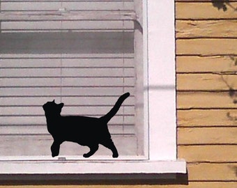 När katten går längs fönsterbrädan, svart väggdekal i vinyl