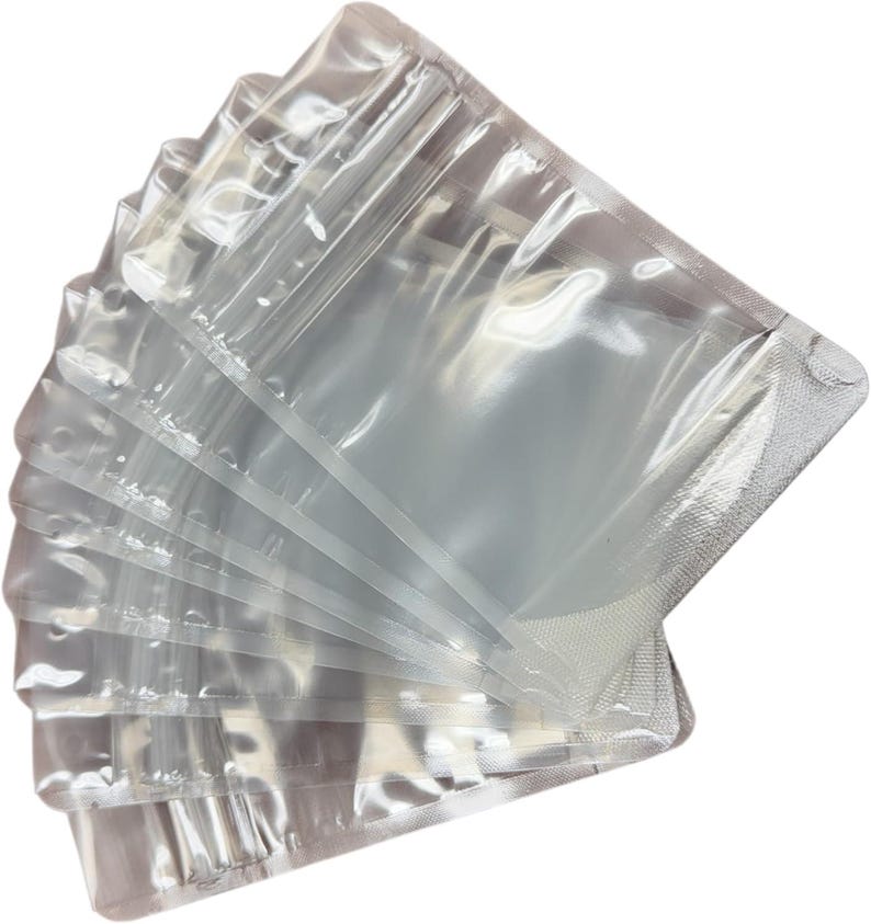May include: A stack of clear, rectangular plastic pouches arranged in a fan shape. Each pouch features a resealable zipper closure at the top and heat-sealed edges on the sides and bottom, providing a transparent view of the interior space.