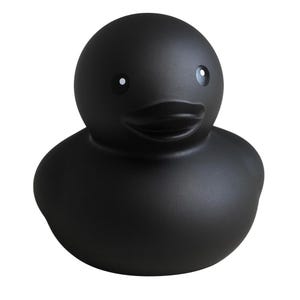 May include: A matte black rubber duck with white eye accents. The duck has a classic design with a rounded body, a small beak, and a smiling expression. This decorative item is suitable for bath time or as a novelty item.