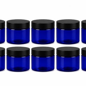 May include: A set of ten cylindrical containers made of translucent cobalt blue plastic, each featuring a flat, circular black screw-top lid. The containers are arranged in two horizontal rows of five, displaying a uniform design and color.
