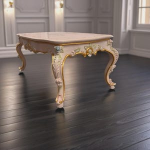 May include: A rectangular coffee table with a pale pink surface and ornate, curved legs. The table features intricate floral carvings highlighted in gold paint, with decorative accents along the apron and legs, showcasing a polished finish.