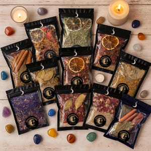 Peut inclure: Plusieurs sachets noirs remplis d'herbes séchées, d'épices et de tranches d'agrumes, disposés sur une surface en bois clair. Les sachets sont scellés avec une tirette en forme de croissant de lune. De petites bougies et des cristaux colorés entourent les sachets.