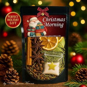 Puede incluir: Una bolsa negra llena de ingredientes para olla a fuego lento, incluyendo palitos de canela, anís estrellado y rodajas de naranja deshidratadas. La bolsa presenta una ilustración de Papá Noel y el texto "Christmas Morning". Una pegatina roja y dorada dice "Perfect Holiday Gift".