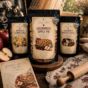 Peut inclure: Trois sachets noirs de parfum d'ambiance botanique pour mijoteuse étiquetés Grandma's Apple Pie, Auntie's Lemon Cake et Grandpa's Morning Coffee, chacun avec un charme cœur argenté, accompagnés d'une fiche recette et d'un rouleau à pâtisserie.