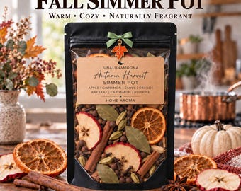 May include: A black stand-up pouch containing a dried autumn harvest simmer pot mix. The label reads: UNALUNAMOONA Autumn Harvest SIMMER POT APPLE | CINNAMON | CLOVE | ORANGE BAY LEAF | CARDAMOM | ALLSPICE HOME AROMA. A green ribbon bow with a leaf charm.