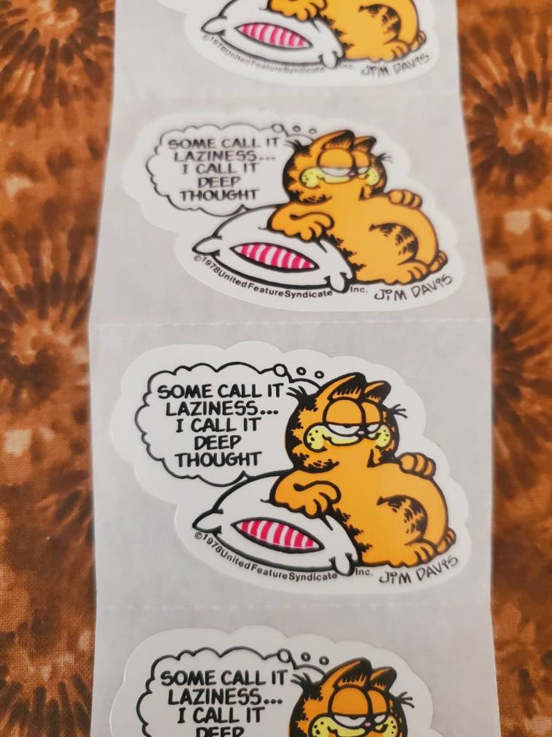May include: A Garfield sticker featuring Garfield the cat sleeping on a pillow with the text "Some call it laziness... I call it deep thought."