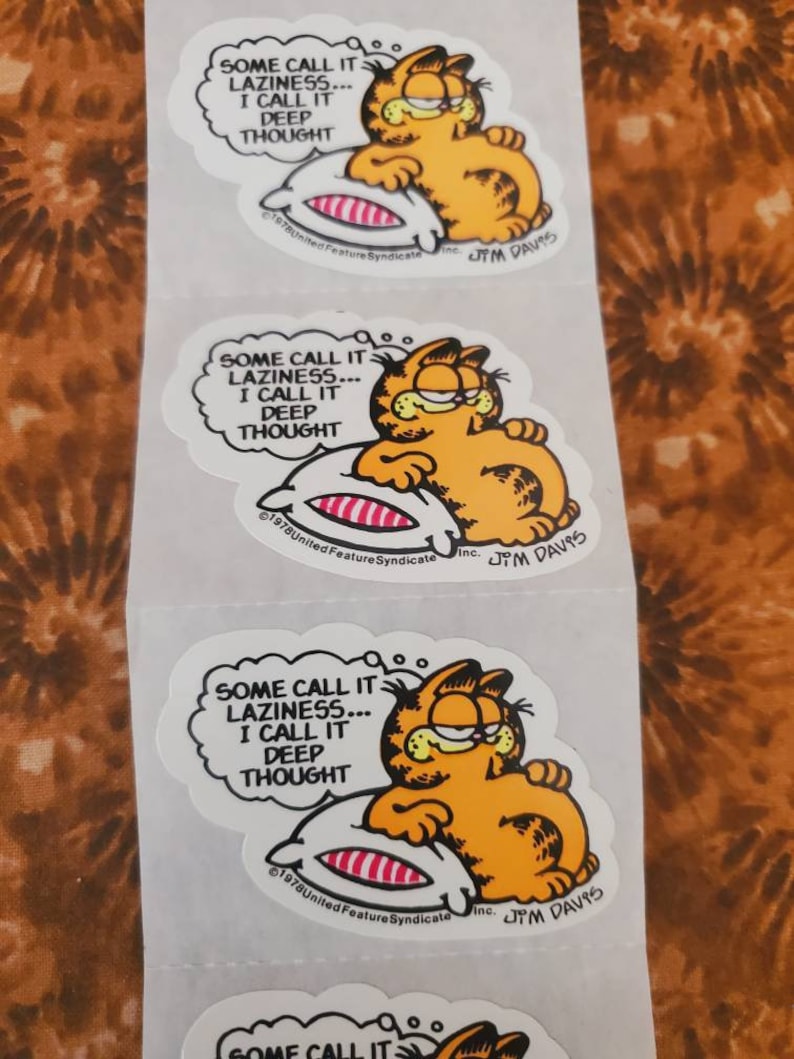 May include: Three Garfield stickers with the text "Some call it laziness... I call it deep thought." Garfield is depicted lying on a pillow with his eyes closed. The stickers are white with black outlines and feature the Garfield copyright information and Jim Davis's signature.