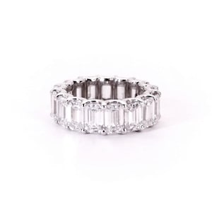May include: A white gold eternity band with a row of emerald-cut diamonds.
