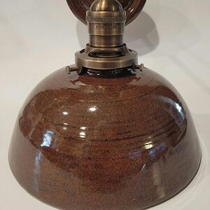 May include: A brown ceramic dome light fixture with a brass socket and mounting plate. The socket has the text "LOT 099/M 250V" on it.