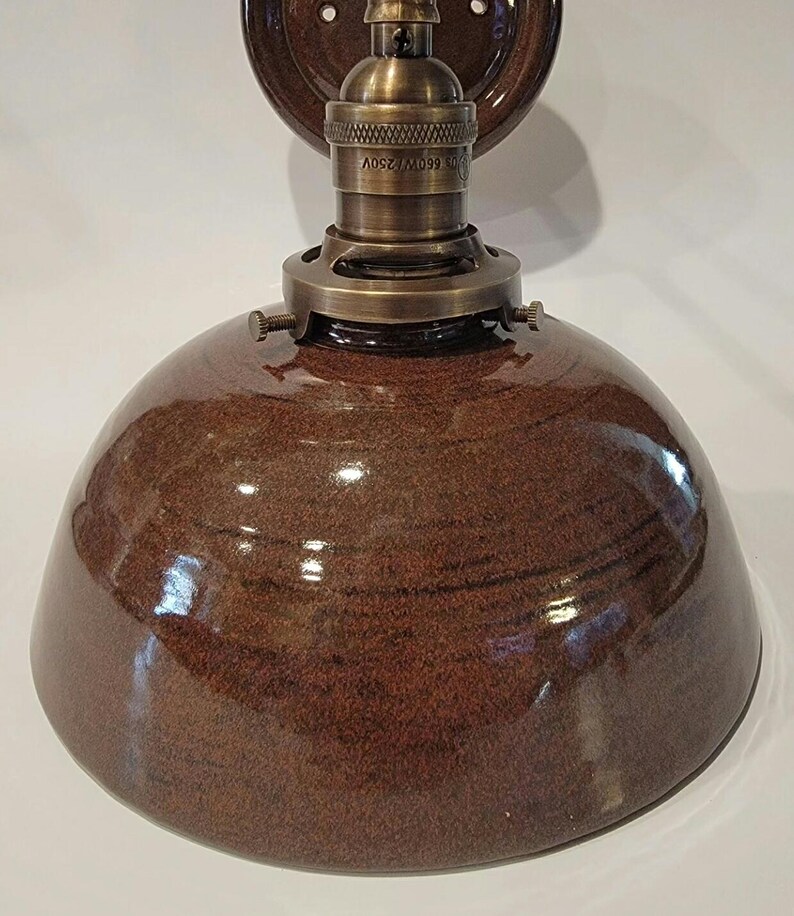 May include: A brown ceramic dome light fixture with a brass socket and mounting plate. The socket has the text "LOT 099/M 250V" on it.