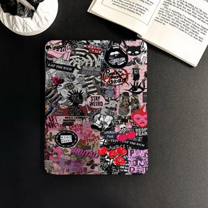Könnte beinhalten: Eine schwarz-rosa stickerbedeckte Hülle mit Punkrock- und Riot-Grrrl-Motiven. Die Hülle ist mit verschiedenen Aufklebern mit Texten wie "EAT THE RICH", "STAY WEIRD" und "RIOT GRRRL" bedeckt. Das Design umfasst Totenköpfe, Herzen und andere Grafiken.