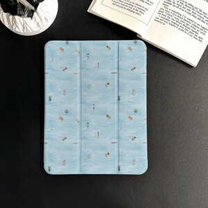 May include: A light blue tablet case featuring a pattern of swimmers and floats in a body of water. The case is open, revealing the screen. The design is repeated across the surface.