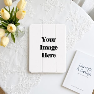May include: A white tablet case with a tri-fold cover featuring the black text Your Image Here, positioned next to a bouquet of yellow tulips in a glass vase and a white book titled Lifestyle & Design Issue 04 Autumn 2024.