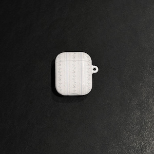 May include: White AirPod case with a floral pattern in light blue and gray. The case has a small loop for attaching to a keychain. The case is rectangular with rounded edges.