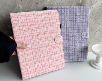 Op de afbeelding: Twee tablethoezen met een textuurpatroon. De ene hoes is roze en de andere paars. Elke hoes heeft een afgeronde flap met een knoopsluiting. De hoezen liggen op een wit oppervlak.