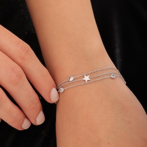 May include: A silver chain bracelet with a star charm and clear cubic zirconia stones.