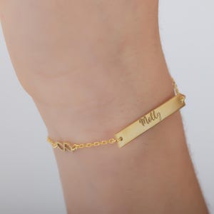 May include: Gold chain bracelet with a personalised bar charm engraved with the name "Molly".