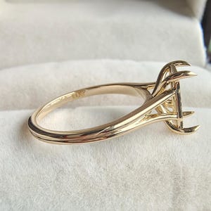 Puede incluir: Un engaste de anillo de oro con una montura de garras de perfil alto diseñada para sostener una piedra preciosa. La banda es lisa y pulida, con un sello 10K visible en la superficie interior. El engaste está vacío, mostrando las garras.