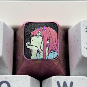 May include: Close-up of a mechanical keyboard with white keycaps. The number 1 key is next to a custom keycap featuring an anime-style illustration of a girl with pink hair. The keycap is a dark pink color.