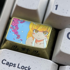 May include: A custom keyboard keycap featuring an anime character with yellow hair and eyes, set against a blue sky with pink cherry blossoms. The keycap has gold-colored sides and Japanese text.