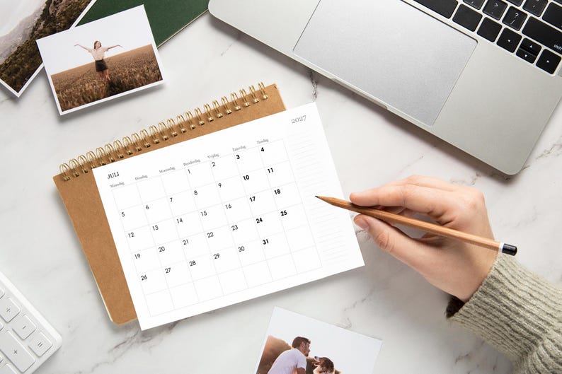 Pode incluir: Um calend&aacute;rio de mesa com espiral para julho de 2027 com capa castanha, apresentando uma grelha branca com texto preto para as datas e dias da semana. O calend&aacute;rio est&aacute; posicionado numa superf&iacute;cie branca ao lado de um computador port&aacute;til.