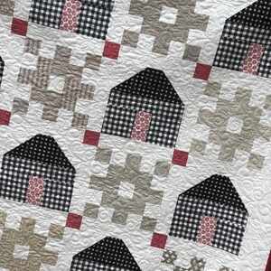 May include: A quilt with a patchwork design featuring black and white gingham squares, red squares, and beige squares. The quilt is quilted with a floral pattern.