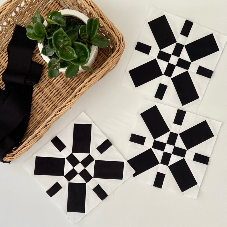 May include: Three black and white quilt blocks with a geometric pattern. The blocks are made of fabric squares sewn together to create a starburst design.
