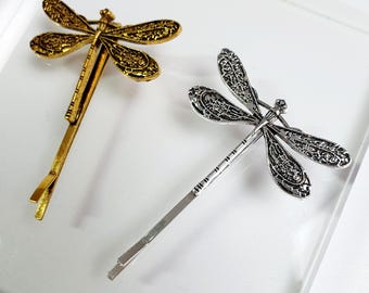 A dragonfly - shaped hair clip available in two color options. DOMANIdesiner