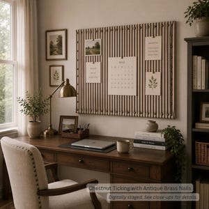 May include: A large rectangular wall-mounted bulletin board featuring chestnut ticking fabric upholstery accented with vertical rows of antique brass nails, displaying various paper notes and a May calendar page.