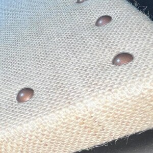 a close-up view of a beige fabric with three small circular buttons on it.