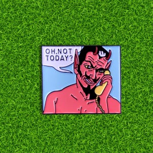 May include: A red enamel pin featuring a cartoon devil with horns and a red beard, holding a yellow phone to his ear. The devil is saying "Oh, not today?" in a speech bubble.
