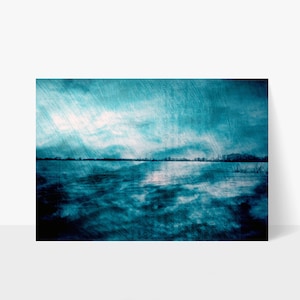 May include: A blue and white abstract landscape with a horizon line and a cloudy sky. The image has a textured, grainy effect.
