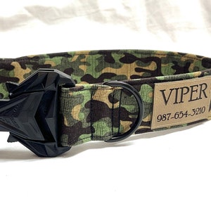 May include: A green, brown, and tan camouflage dog collar with a black buckle and a black D-ring. The collar has a brown leather patch with the text "VIPER 987-654-3210" printed on it.