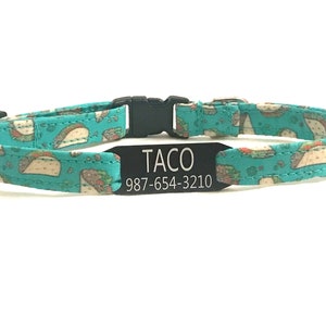 May include: A turquoise blue cat collar with a black buckle and a black tag that reads "TACO 987-654-3210". The collar has a pattern of white tacos on it.