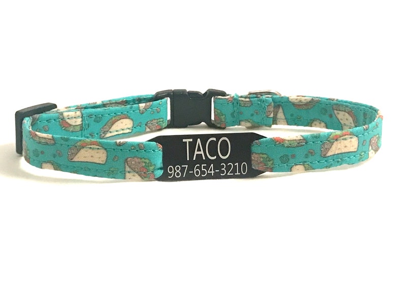 May include: A turquoise blue cat collar with a black buckle and a black tag that reads "TACO 987-654-3210". The collar has a pattern of white tacos on it.