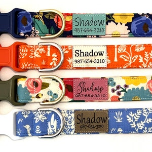 May include: Four dog collars with different floral patterns and colors. Each collar has a silver D-ring and a plastic buckle. A personalized tag with the name "Shadow" and a phone number is attached to each collar.