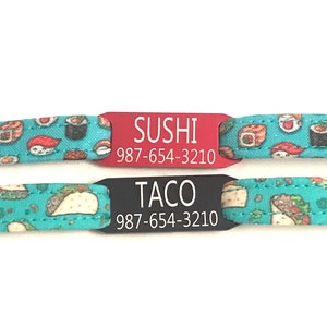 May include: Two personalized pet ID tags with a turquoise background featuring a sushi and taco pattern. The top tag is red with white text that reads "SUSHI 987-654-3210". The bottom tag is black with white text that reads "TACO 987-654-3210".