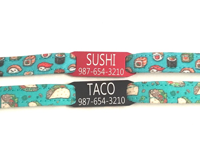 May include: Two personalized pet ID tags with a turquoise background featuring a sushi and taco pattern. The top tag is red with white text that reads "SUSHI 987-654-3210". The bottom tag is black with white text that reads "TACO 987-654-3210".