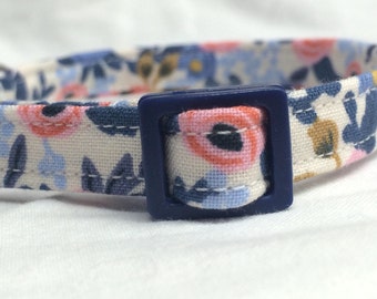 Könnte beinhalten: Ein weißes Baumwoll-Katzenhalsband mit blauem Blumenmuster und einer dunkelblauen Kunststoffschnalle.