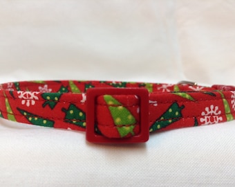 May include: Red cat collar with a green and white Christmas tree pattern and a red buckle.