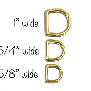May include: Three gold-colored metal D-rings in different sizes. The rings are 1 inch, 3/4 inch, and 5/8 inch wide.